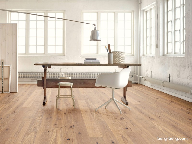 Der edle Holzfußboden verleiht dem hellen Loft eine individuelle wohnliche Note Helles Loft mit reduzierter Einrichtung. Schreibtisch in der Mitte. Edler Holzfußboden von Berg & Berg
