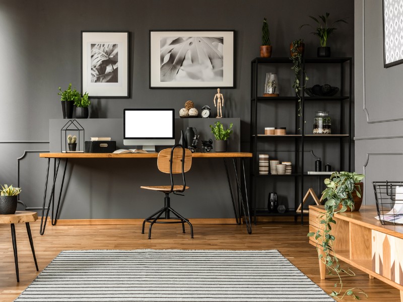 Die graue Wand schenkt dem Raum Tiefe und betont die Holz-Möbel und den Boden Schreibtisch vor grauer Wand. Der Holzfußboden schenkt dem Raum Wärme und Behaglichkeit